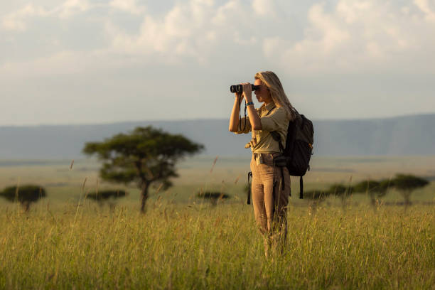 Young woman on a walking safari tour using binoculars in national park Young woman on a walking safari tour using binoculars in national park