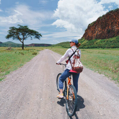 Woman riding a bicycle in Hell's gate national park, Kenya Woman riding a bicycle in Hell's gate national park, Kenya