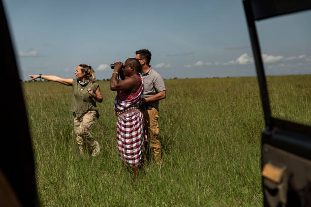 Young people and a safari ranger are observing wildlife on the African Savannah Tourists on a walking safari in Masai Mara